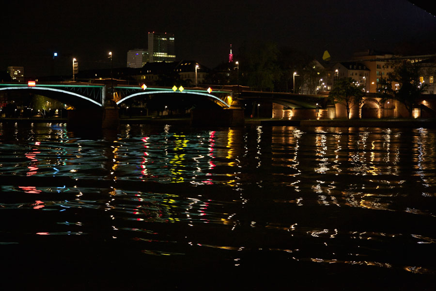 Light-reflecting waves on the River Main in Frankfurt with an illuminated Main Bridge in the background