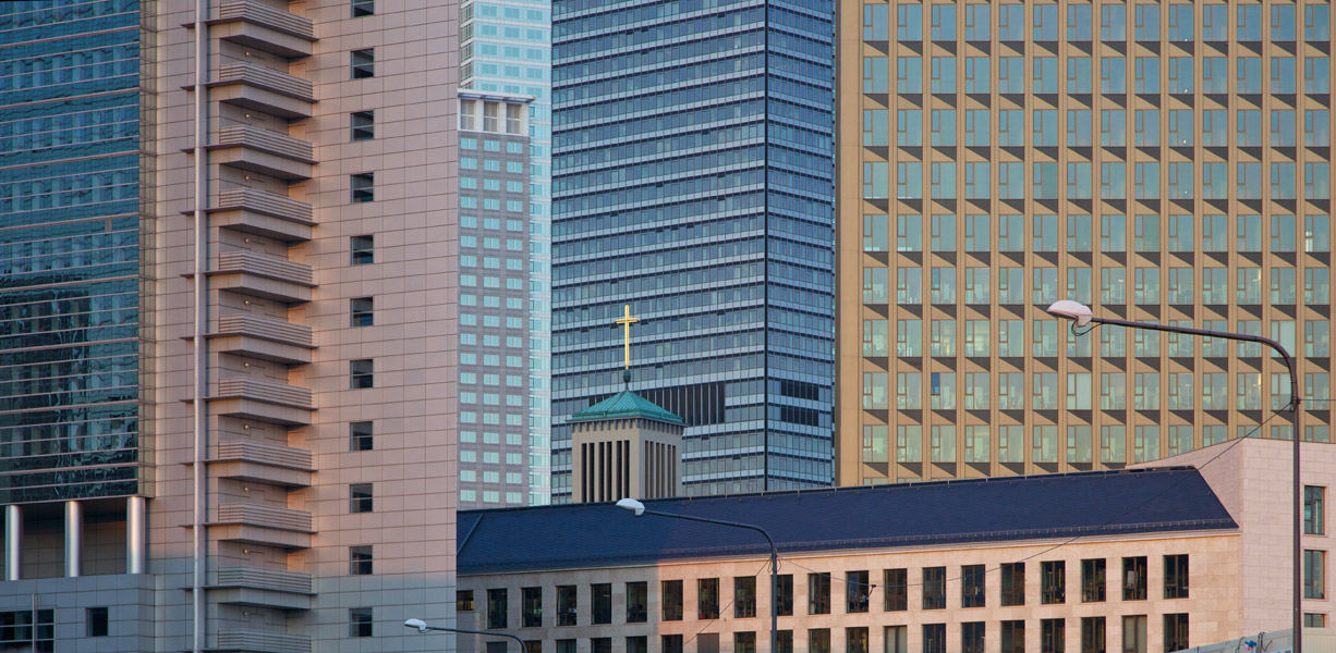 Tower and cross of the Matthäuskirche in Frankfurt between the surrounding skyscrapers